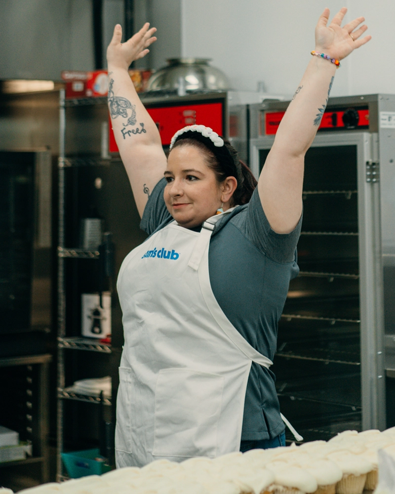 Bridgette Anderson raises her arms in celebration after frosting 100 cupcakes in 2 mins and breaking two Guinness World Records.
