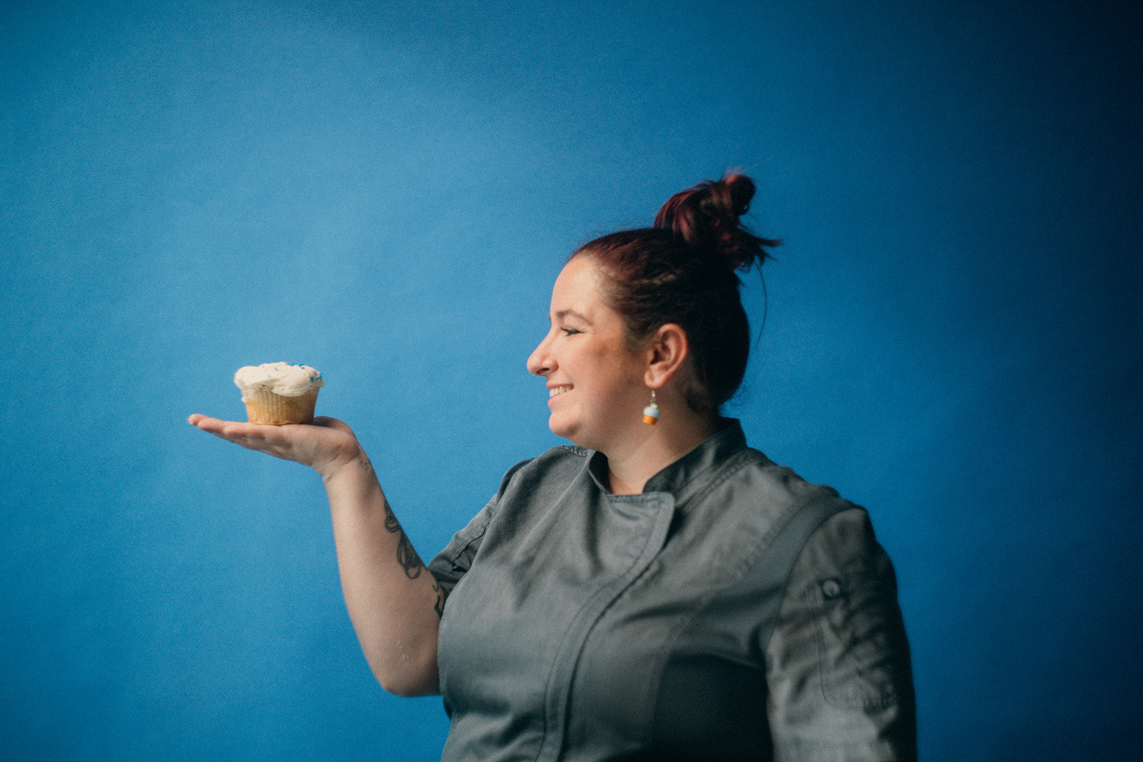 Sam's Club bakery associate Bridgette Anderson holds a cupcake in the palm of her hand, standing against a blue background.