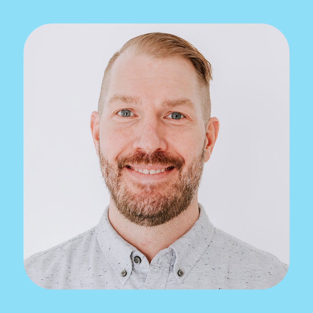 Walmart associate with short hair and beard looks directly at the camera, smiling.