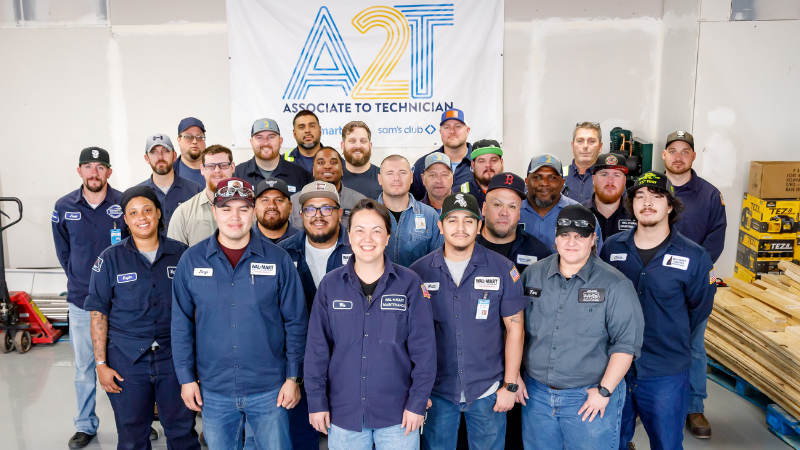 Walmart associates in the Associate-to-Technician program pose in front of an A2T banner.